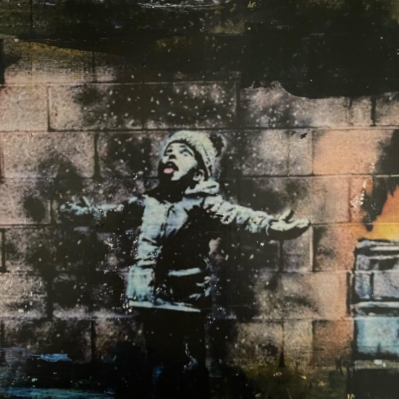 Street art of a child in a raincoat against a textured wall. Zoomed-in details.